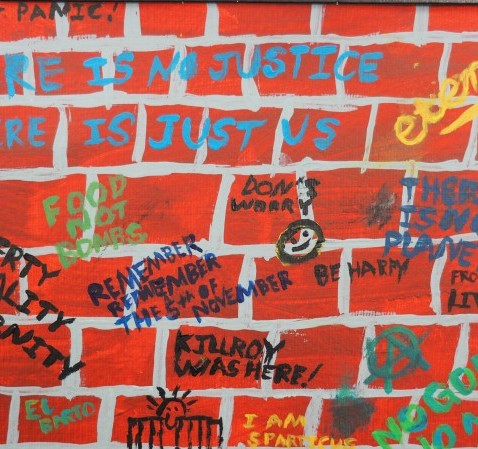 Red brick wall with blue, yellow, green and black graffiti
