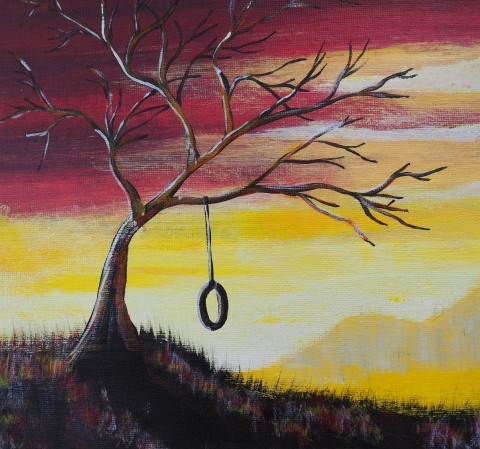 A leafless tree with a tyre swing, in front of a sunset, with yellow hills in the distance