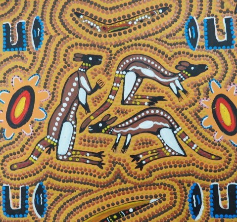 Dot painting of three kangaroos in ochre, black and white, with shapes in blue, red, yellow and black
