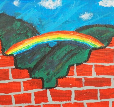 A broken red brick wall in front of a rainbow and green hills, under a blue sky