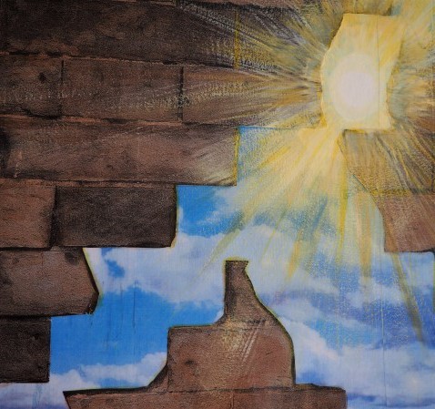 Sun and blue sky showing through a hole in a brown brick wall