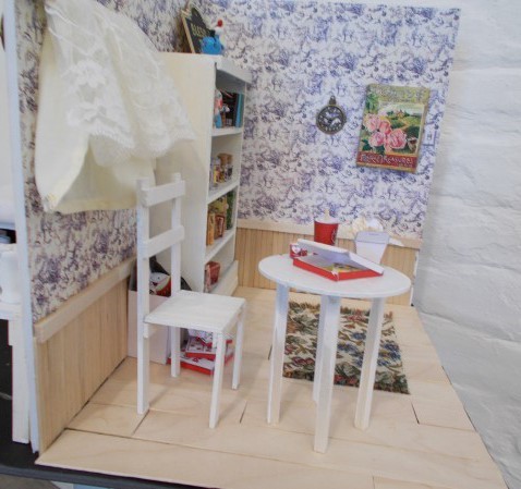 Photograph of a  white table and chair in a small room with a tiled floor