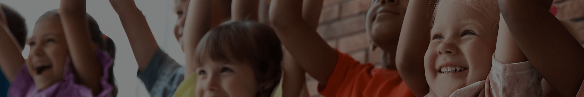 Children standing in a row holding their hands up together in celebration.