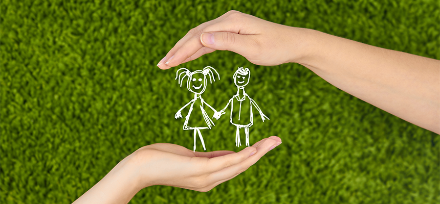 Two hands forming a protective shape around a simple drawing of two children holding hands on green grass.