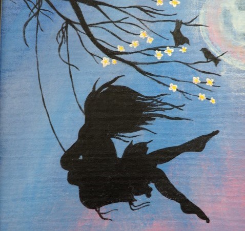 Silhouette of a girl on a swing, in front of a blue sky and the moon