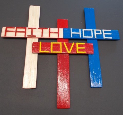 Three crosses - one read, one white and one blue, each with a word Faith, Hope and Love