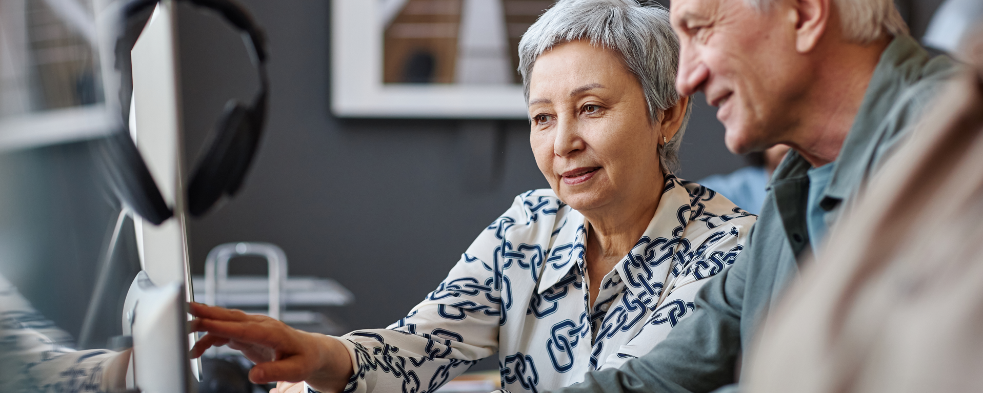 Two elderly people sitting at a computer talking and smiling